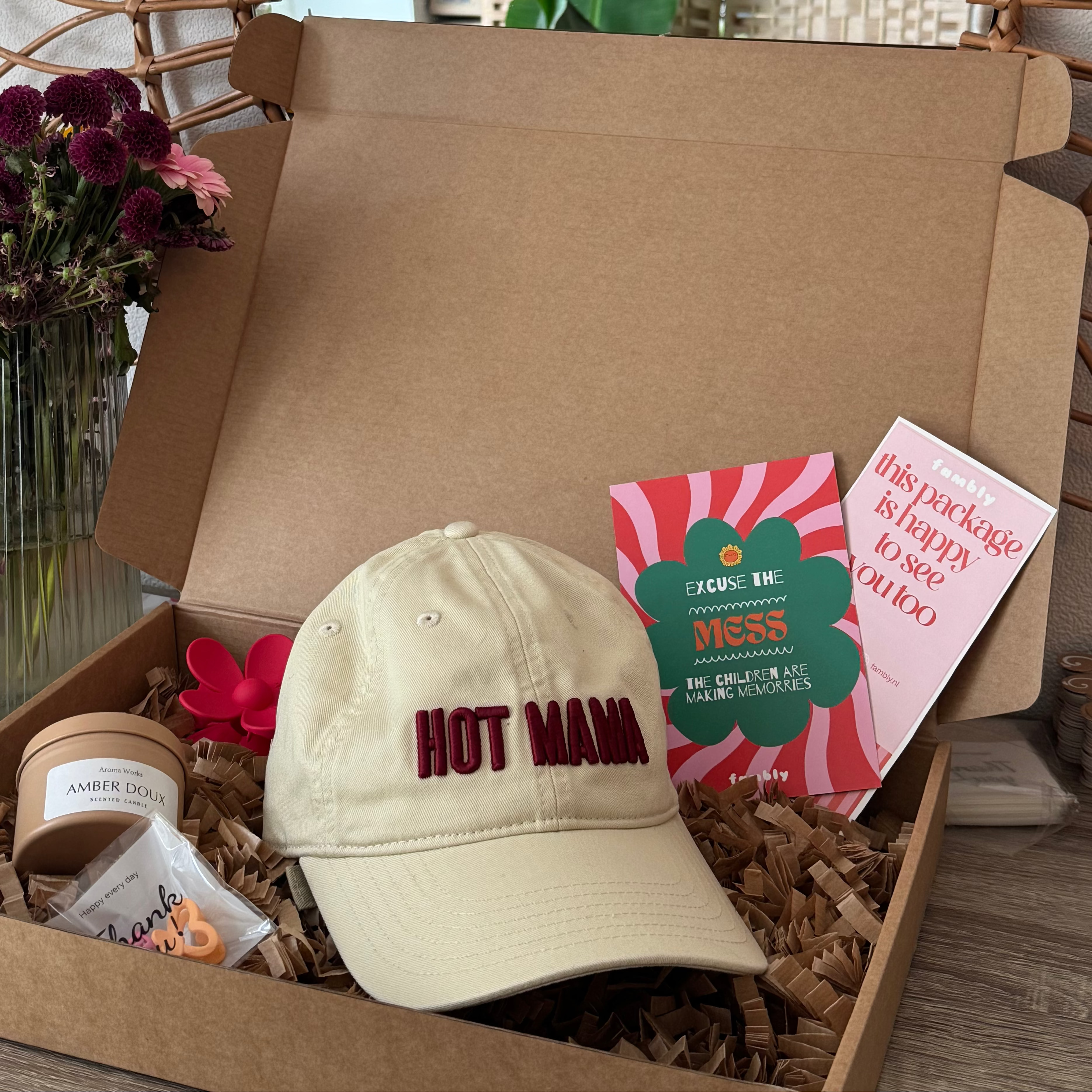 Open box with a cap, cards, and other items on a table with a decorative mirror in the background.